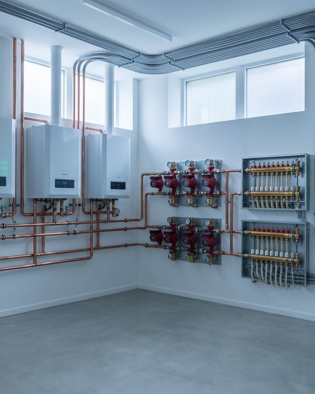Immaculate estate mechanical room with wall-hung boilers, radiant-heat manifolds, circulation pumps and a control panel