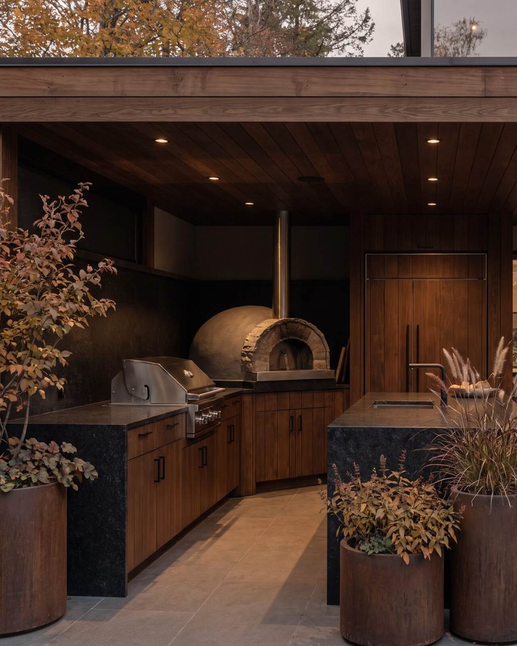 Covered outdoor kitchen with exterior-rated cabinetry, a stone counter, built-in grill and domed pizza oven