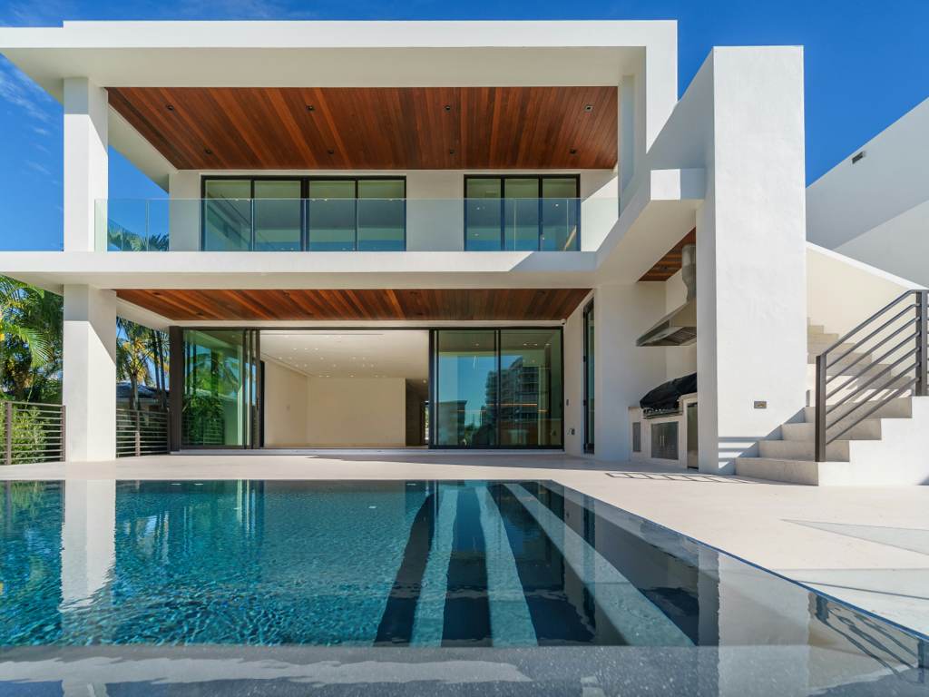Infinity pool wrapping a glass pavilion at golden hour